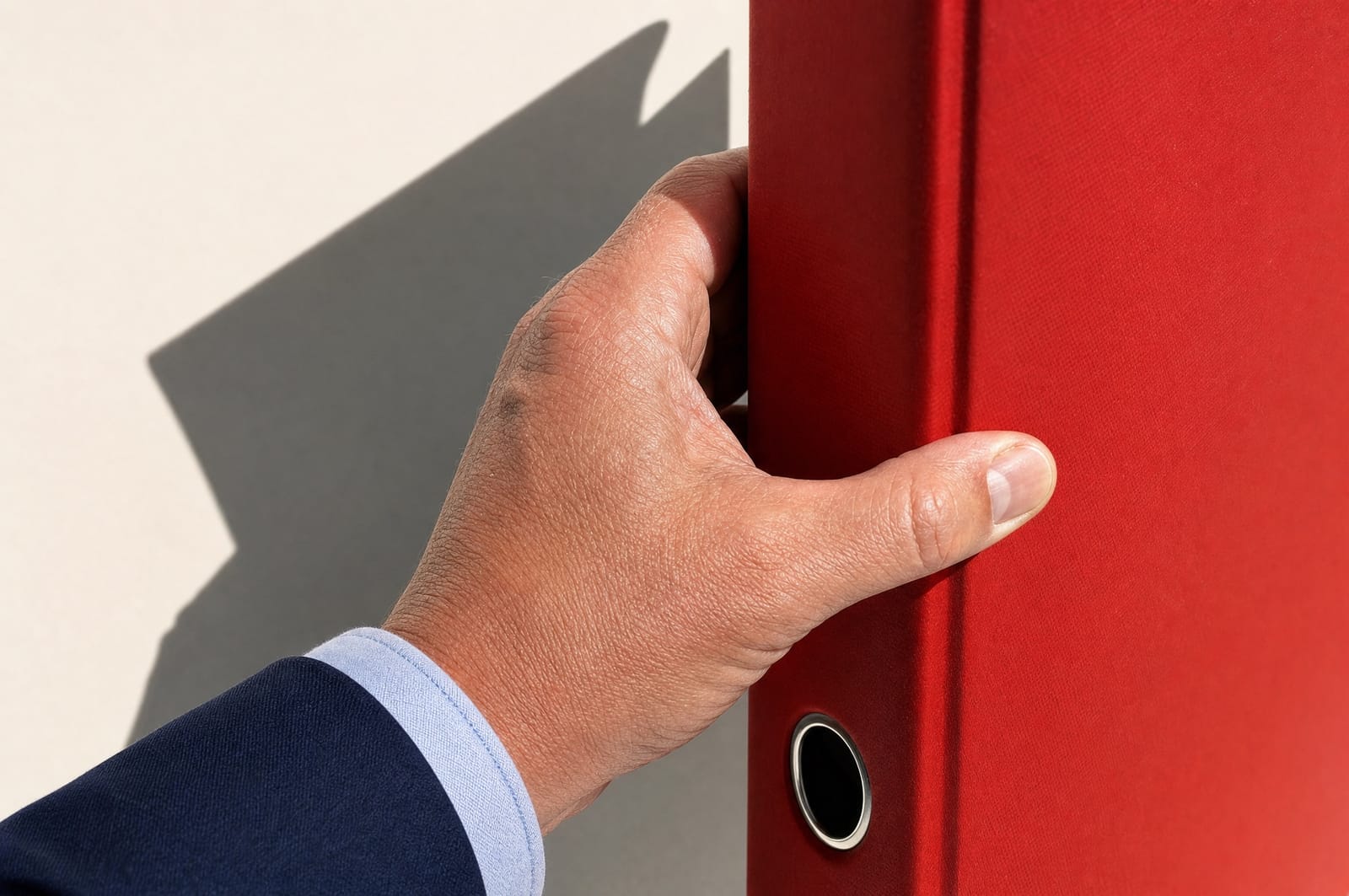 Hand greift einen roten Aktenordner aus dem Regal im Sonnenlicht