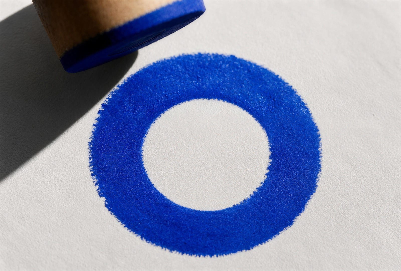 Frisch gesetzter blauer Stempelabdruck auf weissem Papier, der Stempel wird gerade abgehoben